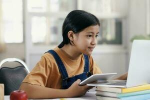 Lycklig asiatisk flicka inlärning uppkopplad på Hem foto