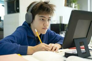 ung pojke använder sig av dator och mobil enhet studerar uppkopplad. foto