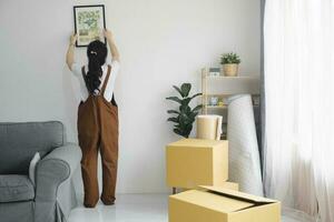 kvinna dekorera ny Hem medan rör på sig i till ny hus eller lägenhet. foto