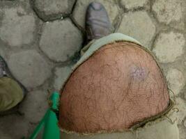 Foto av en Pojkar ben bär trasig brun byxor mot en hexagonal tegel golv i de bakgrund
