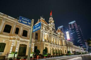 ho chi minh, viet nam - 10 april 2023 saigon stad hall, vincom Centrum torn, färgrik gata trafik och tropisk växter mot de Fantastisk natt. saigon stadens centrum med dess känd landmärken. foto