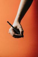 handen tar en penna över en orange bakgrund