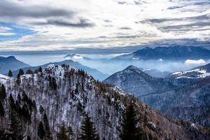 snötäckta alpina toppar i molnen foto