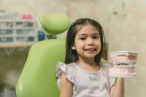 asiatisk flicka i dental stol, med tand borsta. medicin, tandvård och sjukvård begrepp foto