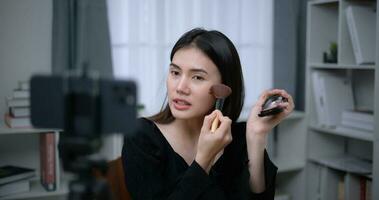 skön ung asiatisk kvinna bloggare visar på vilket sätt till göra upp kosmetika på Hem foto