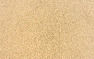 sand strand textur bakgrund i sommar, topp se brun sandig grov yta med Vinka krusning av hav vatten med kopia Plats för sommar baner design, naturlig sand sten förbi de hav foto