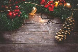 jul bakgrund krans gyllene och röda ornament och kottar på mörk trä bakgrund foto