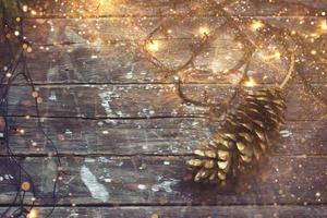 jul bakgrund julbelysning och kotte på mörk trä bakgrund med gyllene glitter