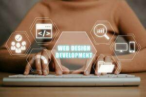 webb design utveckling kodning programmering internet teknologi företag begrepp, ung kvinna hand skriver tangentbord med webb design utveckling ikon på virtuell skärm. foto