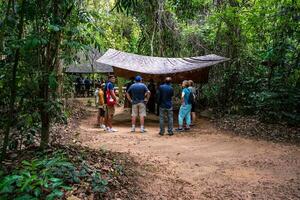 de cu chi tunnlar. en guide demonstrera på vilket sätt en vietcong Dölj in i de tunnel. dess Begagnade i vietnam krig. känd turist attraktion i vietnam. stock Foto