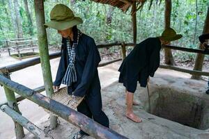 de cu chi tunnlar. en guide demonstrera på vilket sätt en vietcong Dölj in i de tunnel. dess Begagnade i vietnam krig. känd turist attraktion i vietnam. stock Foto