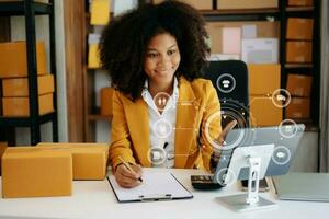 afrikansk ung oman hand använder sig av en bärbar dator, smartphone och läsplatta och skrivning anteckningsbok på de kontor av henne företag uppkopplad handla. i Hem med virtuell ikon foto