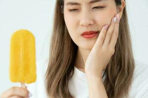 asiatisk kvinna känna känslig tänder efter äter is grädde, kvinna lida tand, förfall problem, dental vård, tand extraktion, förfall problem, dålig andetag, gingival lågkonjunktur, oral hygien instruktion foto