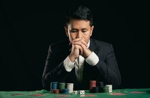 asiatisk man -handlare eller croupier blandar poker kort vadhållning i kasino på svart bakgrund av grön tabell, -handlare man inbjudan slå vad spelar kort. kasino, poker, poker spel begrepp. foto