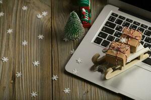 små trä- släde med jul presenterar på en bärbar dator. foto