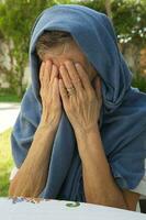 ett gammal kvinna är dölja henne tårar förbi har täckt henne ansikte med händer foto