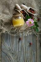 vild reste sig höft honung i en glas flaska på en trä- yta. foto