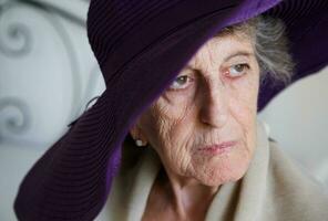 gammal caucasian kvinna i en violett hatt foto