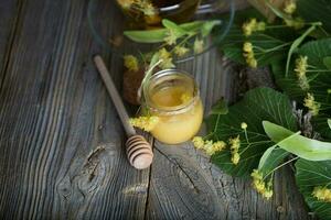 lind blommar honung i en glas flaska på en trä- yta. foto