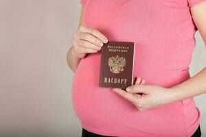 ung gravid mellan 30 och 35 år gammal kvinna håller henne ryska resa passera. foto