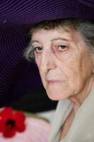 gammal caucasian kvinna i en violett hatt foto