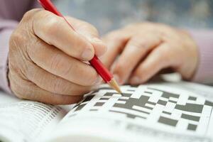 asiatisk äldre kvinna spelar sudoku pussel spel till öva hjärna Träning för demens förebyggande, alzheimers sjukdom. foto