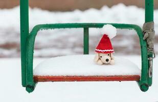 plysch hund i santa hatt på en snöig gunga foto