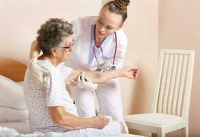 geriatriker hjälper en senior kvinna till stå upp foto