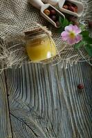 vild reste sig höft honung i en glas flaska på en trä- yta. foto