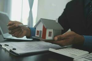 hus modell med verklig egendom ombud och kund diskuterar för kontrakt till köpa hus, försäkring eller lån verklig fastighet, real egendom begrepp. foto