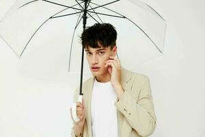 trevlig ung kille med ett öppen paraply i en kostym ljus bakgrund foto