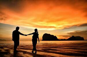 romantisk par innehav händer på solnedgång på strand foto