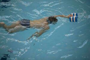 pojke i en simning keps och simning glasögon i de slå samman. de barn är engagerad i de simning sektion. foto