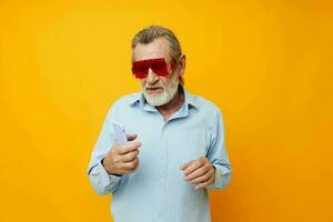 porträtt äldre man i modern röd glasögon med en telefon isolerat bakgrund foto