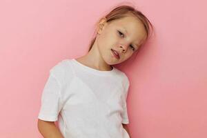 porträtt av Lycklig leende barn flicka i en vit t-shirt leende rosa bakgrund foto