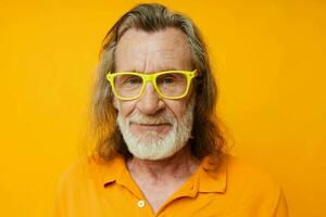 senior gråhårig man gul t-shirt och glasögon Framställ gul bakgrund foto