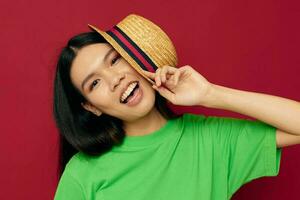 porträtt asiatisk skön ung kvinna leende grön t-shirt hatt Framställ mode röd bakgrund oförändrad foto