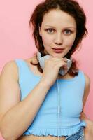 ung kvinna tonåring bär hörlurar musik underhållning rosa bakgrund oförändrad foto