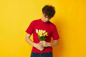 ung lockigt hår man i en röd t-shirt en bukett av blommor Semester gåva livsstil oförändrad foto