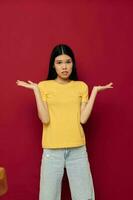 porträtt asiatisk skön ung kvinna gester med hans händer i en gul t-shirt tillfällig ha på sig studio modell oförändrad foto