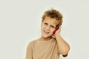 rolig lockigt pojke talande på de telefon ljus bakgrund foto