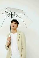 en ung man innehav ett paraply i de händer av Framställ mode ljus bakgrund oförändrad foto