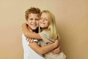pojke och flicka i t-tröjor kramar beige bakgrund vänskap foto