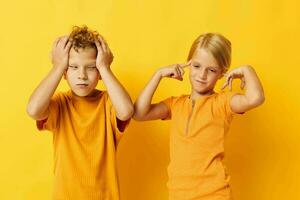 porträtt av söt barn i gul t-tröjor stående sida förbi sida barndom känslor gul bakgrund oförändrad foto