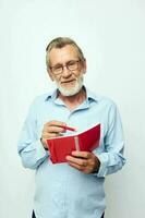 porträtt av Lycklig senior man med röd anteckningsbok och penna ljus bakgrund foto