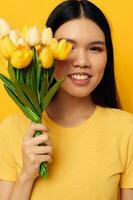 kvinna i en gul t-shirt t-shirt med en bukett av blommor Semester gul bakgrund oförändrad foto