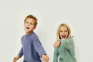 pojke och flicka i flerfärgad tröjor Framställ för roligt ljus bakgrund foto