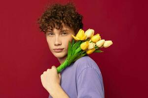 en ung man innehav en gul bukett av blommor lila t-tröjor isolerat bakgrund oförändrad foto