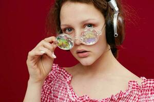 flicka bär hörlurar glasögon med diamant närbild röd bakgrund oförändrad foto