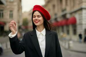 mode kvinna porträtt leende med tänder stående på de gata i främre av de stad turist i eleganta kläder med röd mun och röd basker, resa, filmiska Färg, retro årgång stil, urban mode. foto